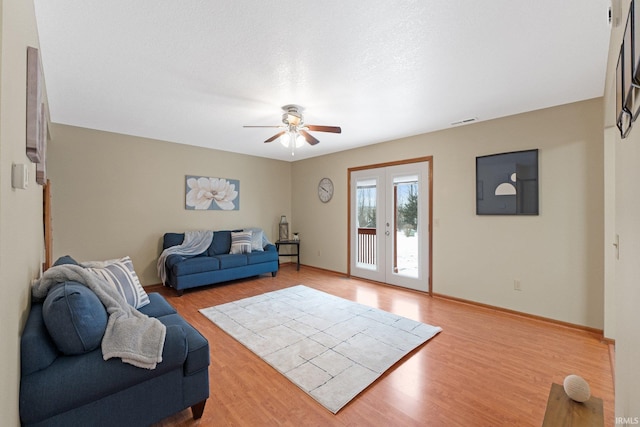 living room featuring ceiling fan, light hardwood / wood-style floors, and french doors