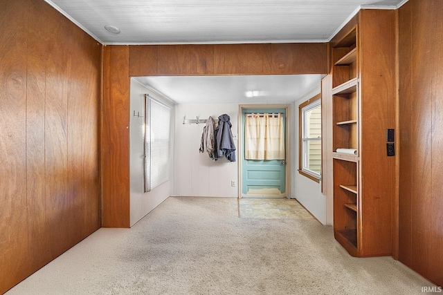 interior space featuring light colored carpet, crown molding, and wood walls