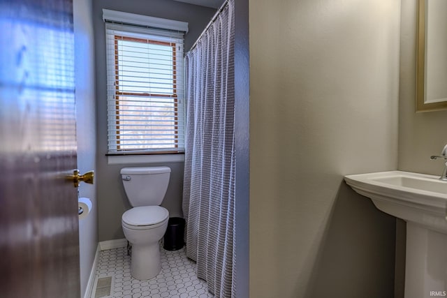 bathroom featuring tile patterned flooring, toilet, a healthy amount of sunlight, and sink