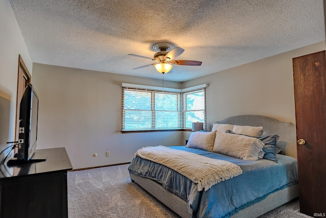 bedroom with ceiling fan, carpet floors, and a textured ceiling