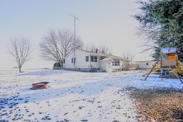 snow covered property featuring a playground and central air condition unit