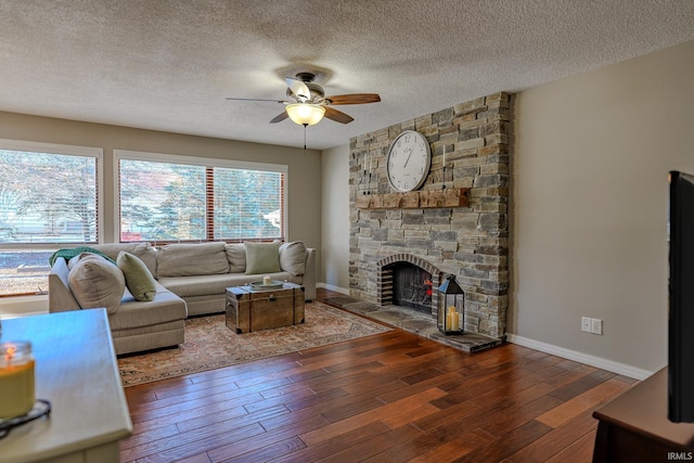 living room featuring ceiling fan, a fireplace, dark hardwood / wood-style floors, and a textured ceiling