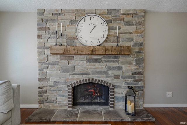 room details featuring a stone fireplace, wood-type flooring, and a textured ceiling