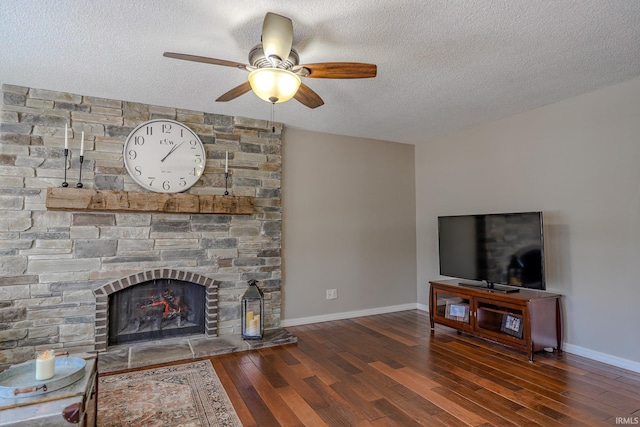 living room with a textured ceiling, a fireplace, ceiling fan, and dark wood-type flooring