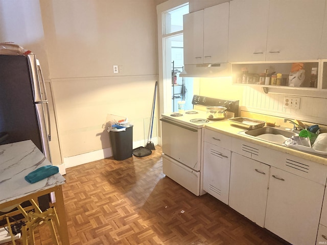 kitchen featuring range, light parquet floors, sink, stainless steel fridge, and white cabinetry