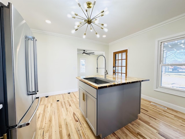 kitchen with gray cabinetry, a center island with sink, sink, ornamental molding, and high quality fridge