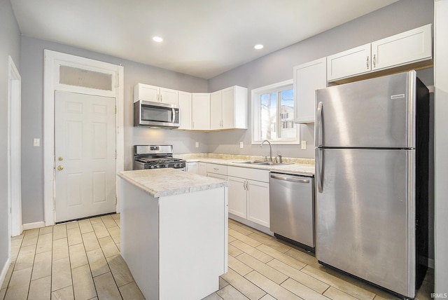 kitchen with white cabinetry, sink, a kitchen island, and appliances with stainless steel finishes