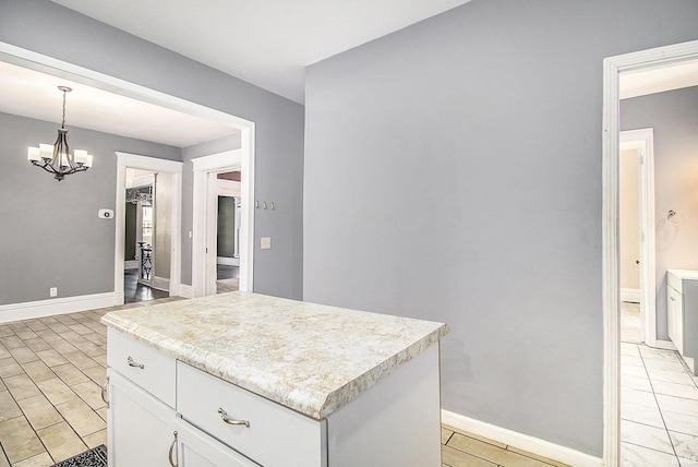 kitchen with white cabinets, a center island, decorative light fixtures, and an inviting chandelier