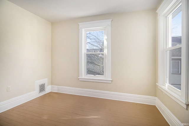 unfurnished room featuring plenty of natural light and wood-type flooring