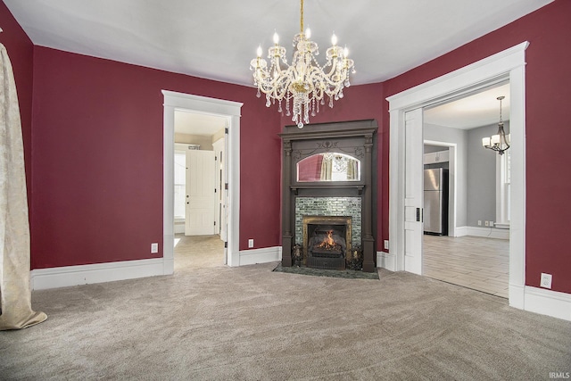 unfurnished living room with carpet floors, a fireplace, and a chandelier