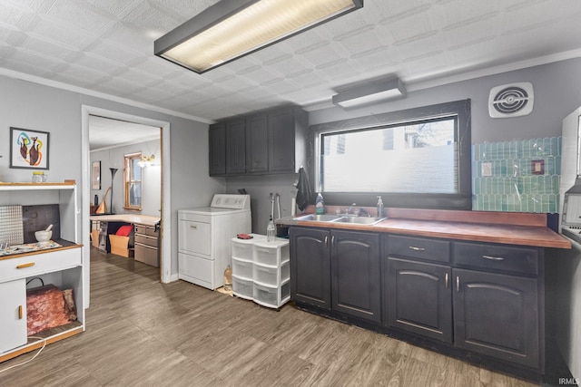 kitchen with washer / clothes dryer, hardwood / wood-style flooring, ornamental molding, and sink