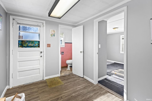 entrance foyer with dark hardwood / wood-style floors, ornamental molding, and tile walls