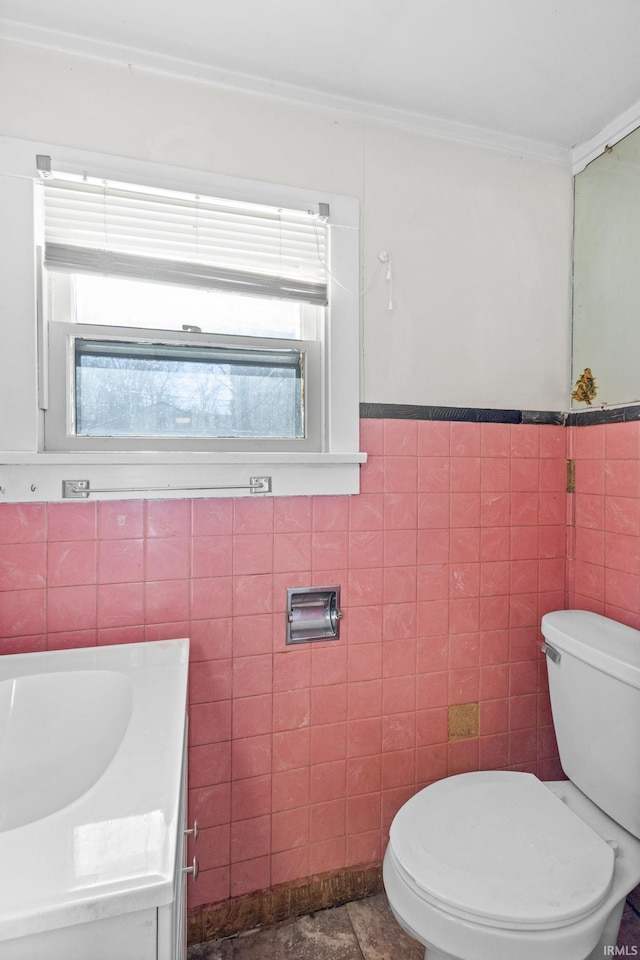 bathroom featuring vanity, toilet, and tile walls