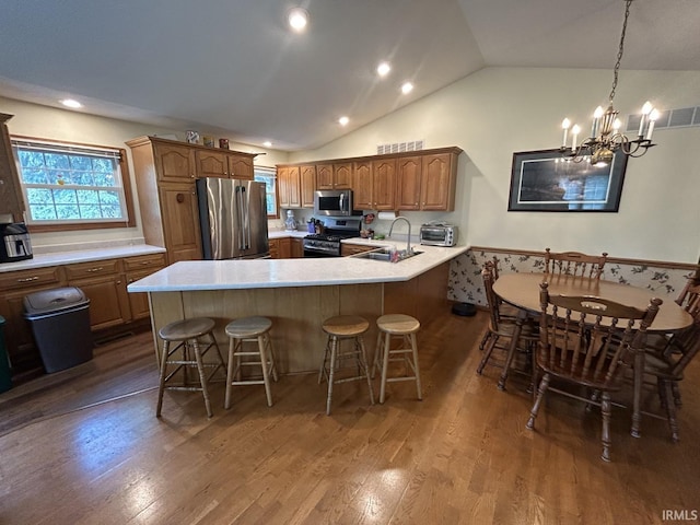 kitchen featuring an inviting chandelier, sink, appliances with stainless steel finishes, kitchen peninsula, and a breakfast bar area