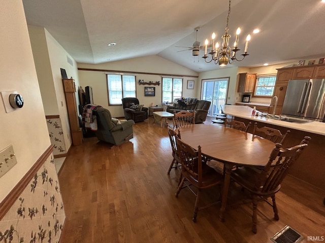 dining room featuring ceiling fan with notable chandelier, hardwood / wood-style flooring, vaulted ceiling, and sink