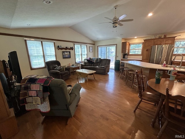 living room featuring a textured ceiling, vaulted ceiling, ceiling fan, sink, and hardwood / wood-style floors