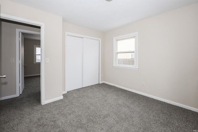 unfurnished bedroom featuring dark colored carpet and a closet