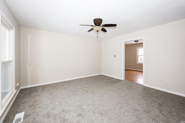 spare room with dark colored carpet and ceiling fan