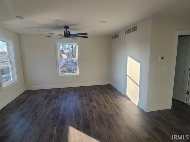 spare room with dark hardwood / wood-style flooring, a wealth of natural light, and ceiling fan