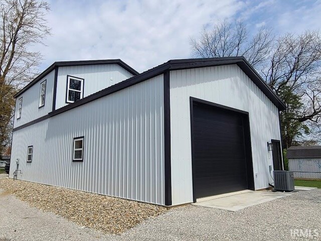 511 W Boston St, Syracuse, IN 46567 - view of property exterior with gravel driveway, an outbuilding, cooling unit, and a garage