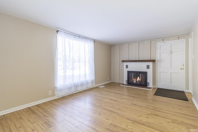 unfurnished living room featuring a brick fireplace and light hardwood / wood-style flooring