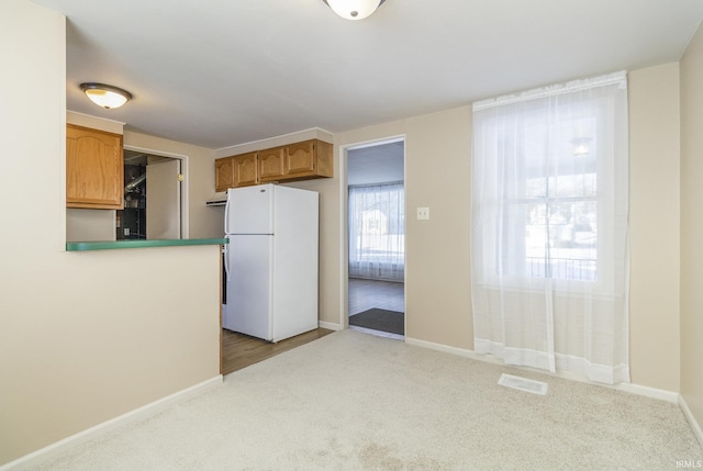 kitchen featuring white fridge, kitchen peninsula, and light carpet