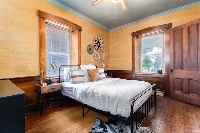 bedroom with crown molding, ceiling fan, wooden walls, and dark wood-type flooring