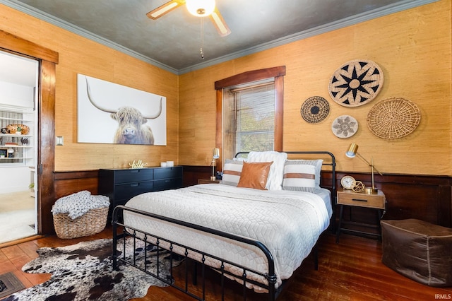 bedroom with ceiling fan, dark hardwood / wood-style floors, crown molding, and wooden walls