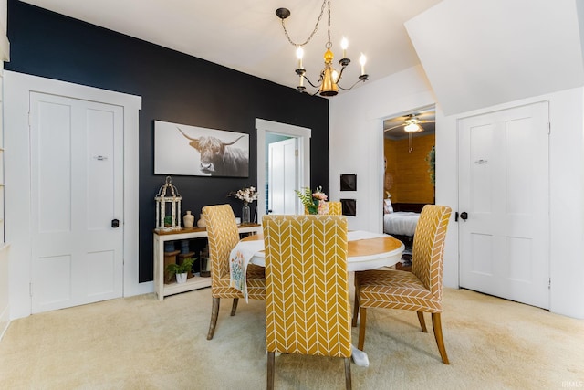 dining space featuring ceiling fan with notable chandelier and light colored carpet