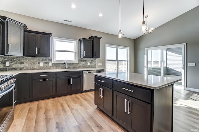 kitchen featuring hanging light fixtures, sink, vaulted ceiling, tasteful backsplash, and stainless steel appliances