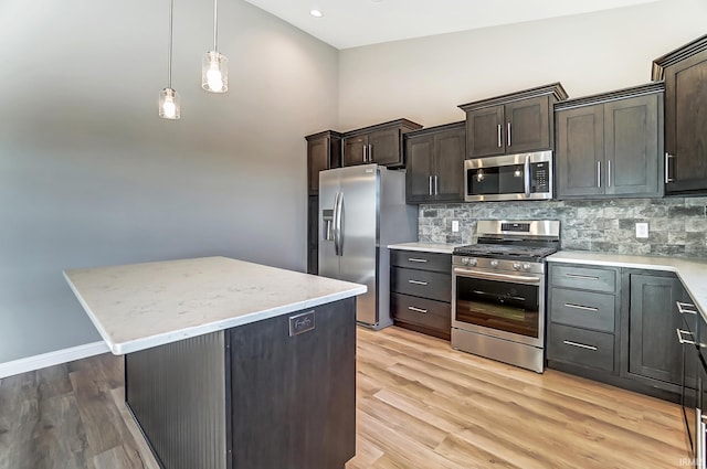 kitchen featuring pendant lighting, backsplash, a kitchen island, dark brown cabinetry, and stainless steel appliances