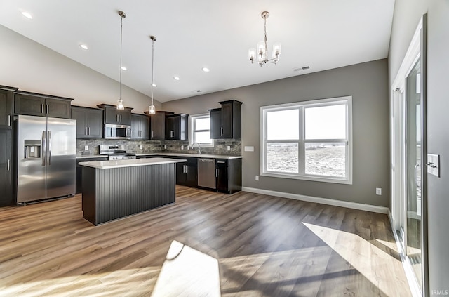 kitchen with a center island, an inviting chandelier, light wood-type flooring, decorative light fixtures, and stainless steel appliances