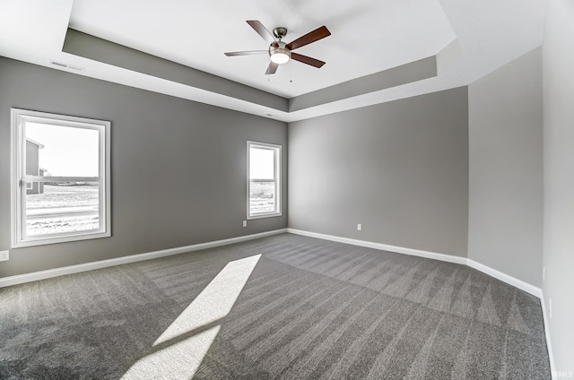 carpeted empty room with a raised ceiling and ceiling fan