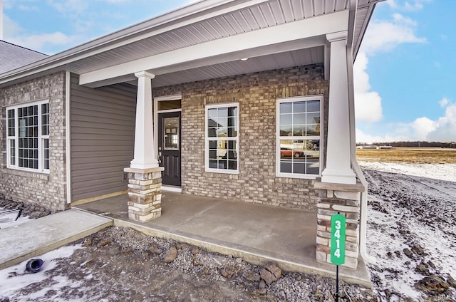 snow covered property entrance with a porch