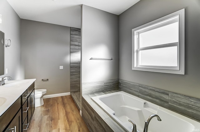 bathroom featuring wood-type flooring, vanity, toilet, and tiled tub