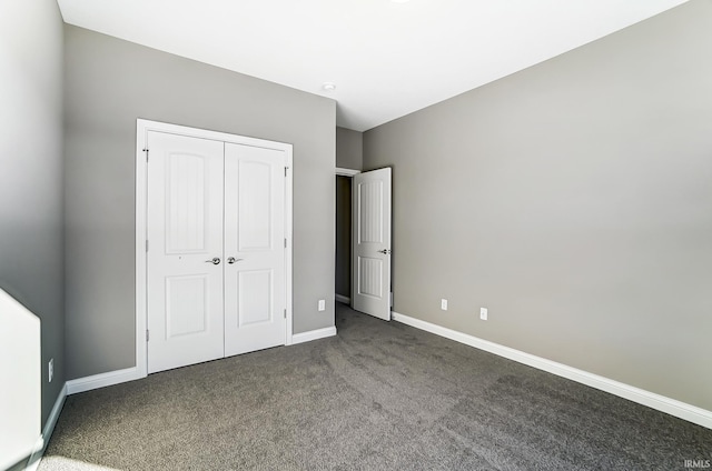 unfurnished bedroom with dark colored carpet and a closet