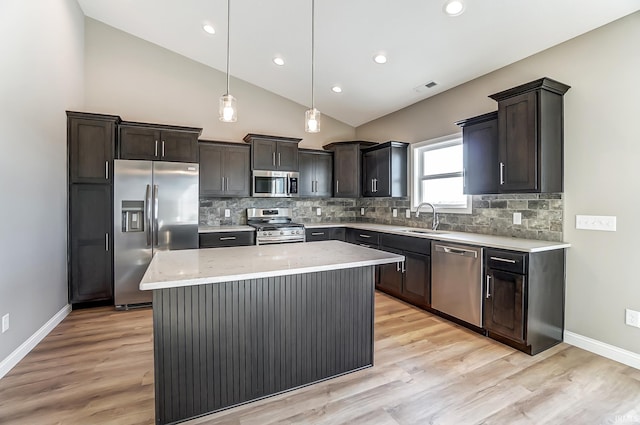 kitchen featuring appliances with stainless steel finishes, vaulted ceiling, sink, pendant lighting, and a kitchen island