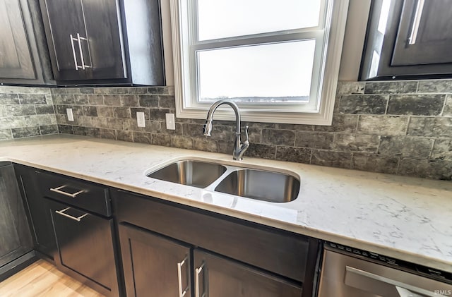 kitchen featuring light stone countertops, light wood-type flooring, dark brown cabinetry, sink, and dishwasher