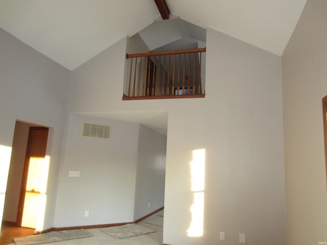 carpeted empty room featuring vaulted ceiling with beams