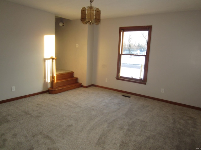 unfurnished room with carpet flooring and a notable chandelier