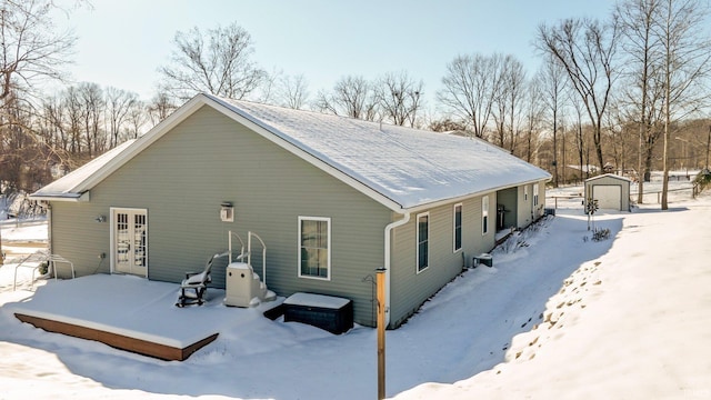 snow covered property with a garage and an outdoor structure