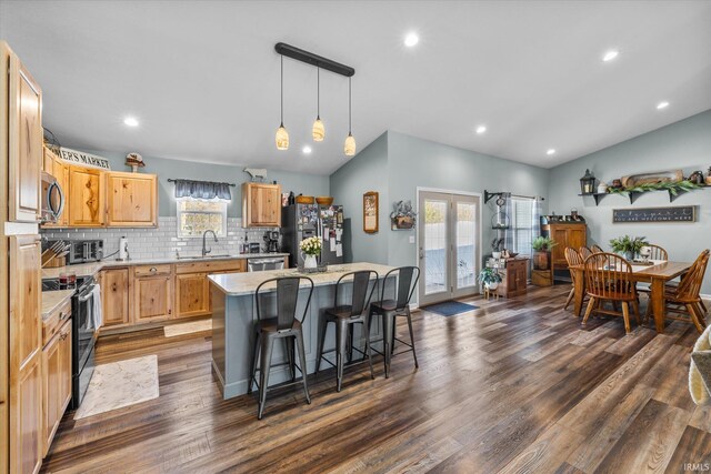 kitchen featuring appliances with stainless steel finishes, dark wood-type flooring, pendant lighting, a kitchen island, and lofted ceiling