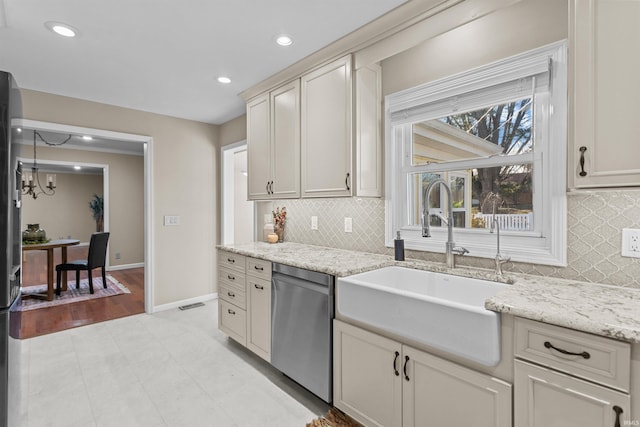 kitchen with an inviting chandelier, sink, stainless steel dishwasher, light stone countertops, and tasteful backsplash