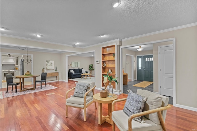 living room with wood-type flooring, a textured ceiling, built in features, and ornamental molding