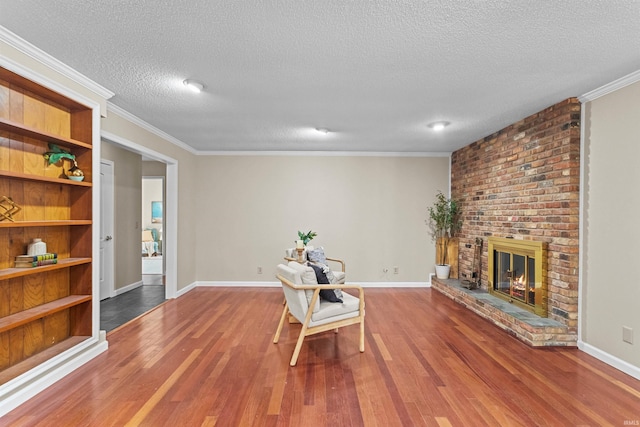 sitting room featuring a fireplace, a textured ceiling, hardwood / wood-style flooring, and ornamental molding