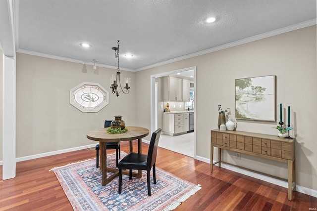 dining area with crown molding, hardwood / wood-style floors, a textured ceiling, and an inviting chandelier