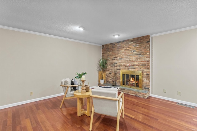 dining space with a fireplace, crown molding, hardwood / wood-style floors, and a textured ceiling