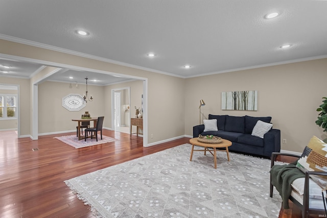 living room with a notable chandelier, light hardwood / wood-style floors, and ornamental molding