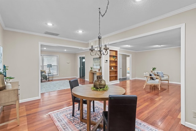 dining space with hardwood / wood-style floors, crown molding, and a chandelier