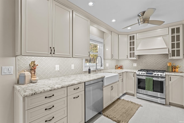 kitchen with ceiling fan, sink, stainless steel appliances, light stone counters, and custom range hood